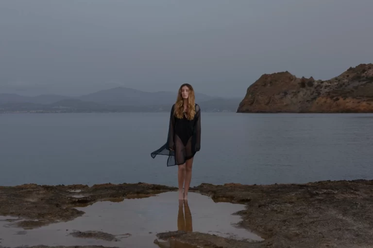 Captivating Photoshoot on Paros Island: A woman striking a pose on the rugged beach rocks of Paros Island, expertly captured by local photographer Pranvera Dautllari, hailing from Athens and Paros
